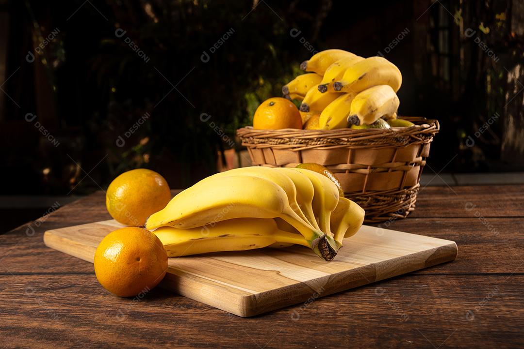 Bananas E Laranjas Em Mesa De Madeira Polida Imagem JPG