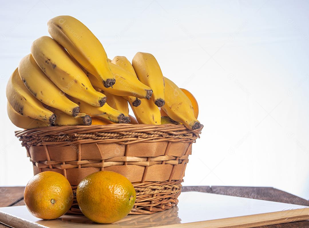 Bananas E Laranjas Em Uma Cesta Colocada Em Madeira Polida Imagem JPG