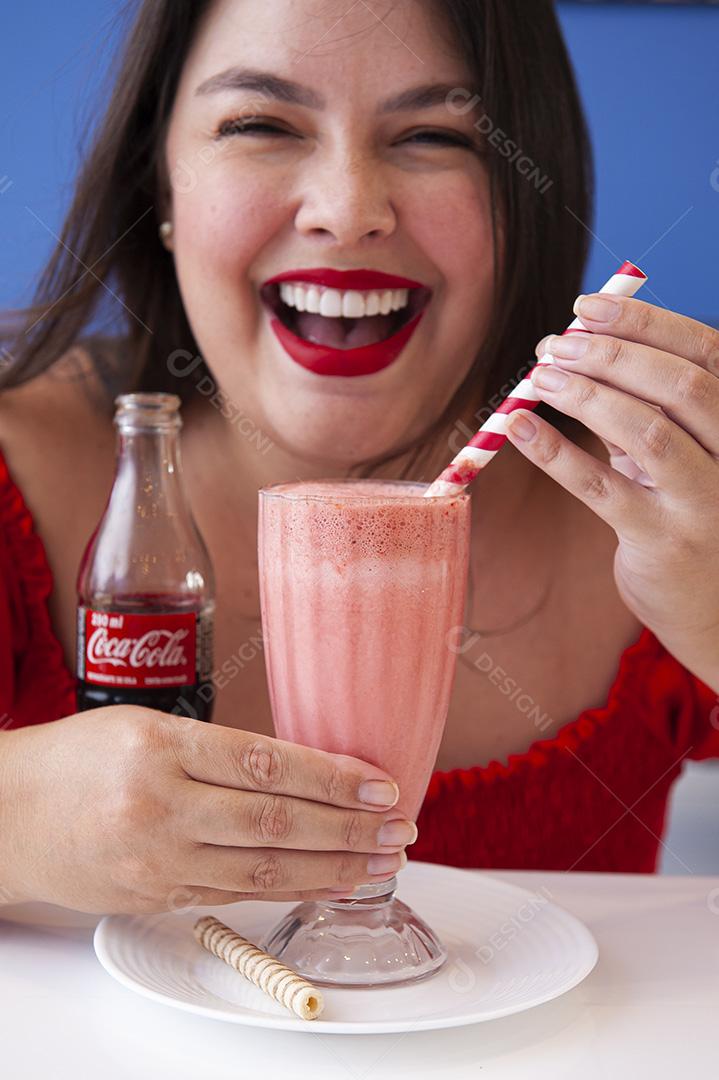 Menina bonita e sorridente tomando uma xícara de sorvete com coca cola