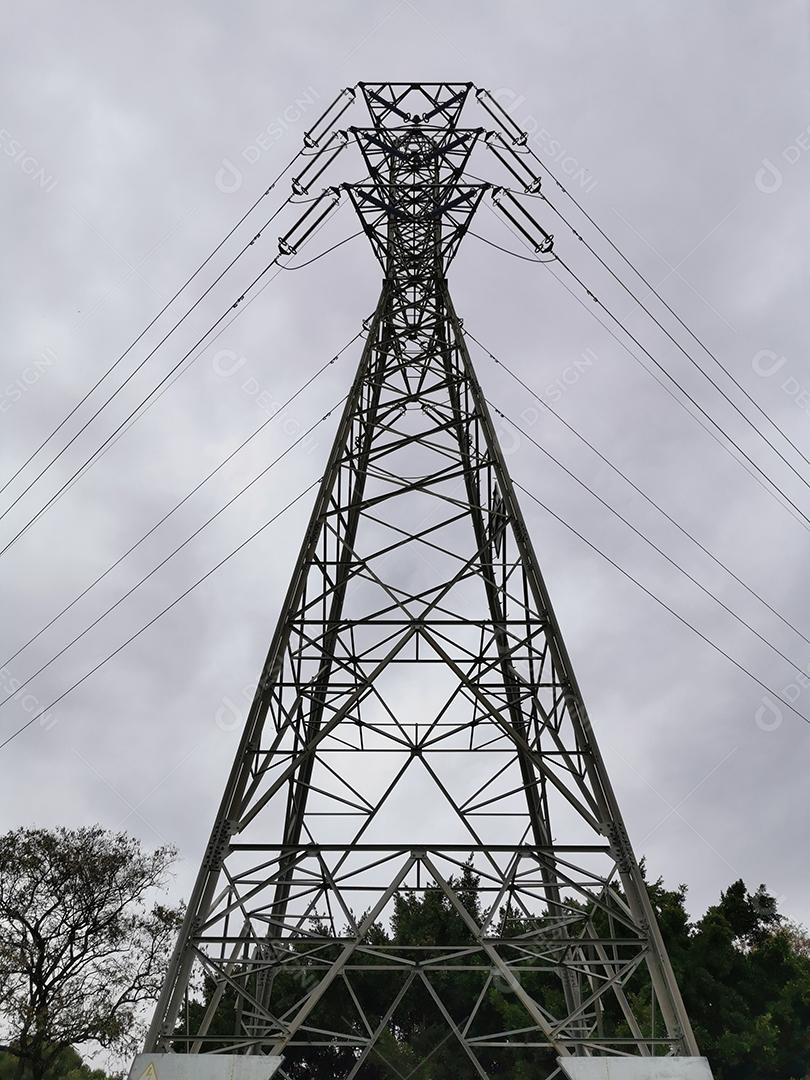 Vista vertical de uma torre de energia elétrica com céu com nuvens.