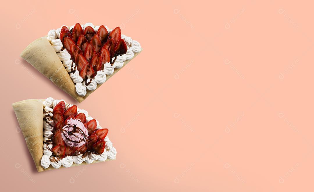 Vista superior do crepe ou panqueca fina com pedaços de morango com sorvete de morango, pão de chocolate e chantilly em um fundo rosa claro.