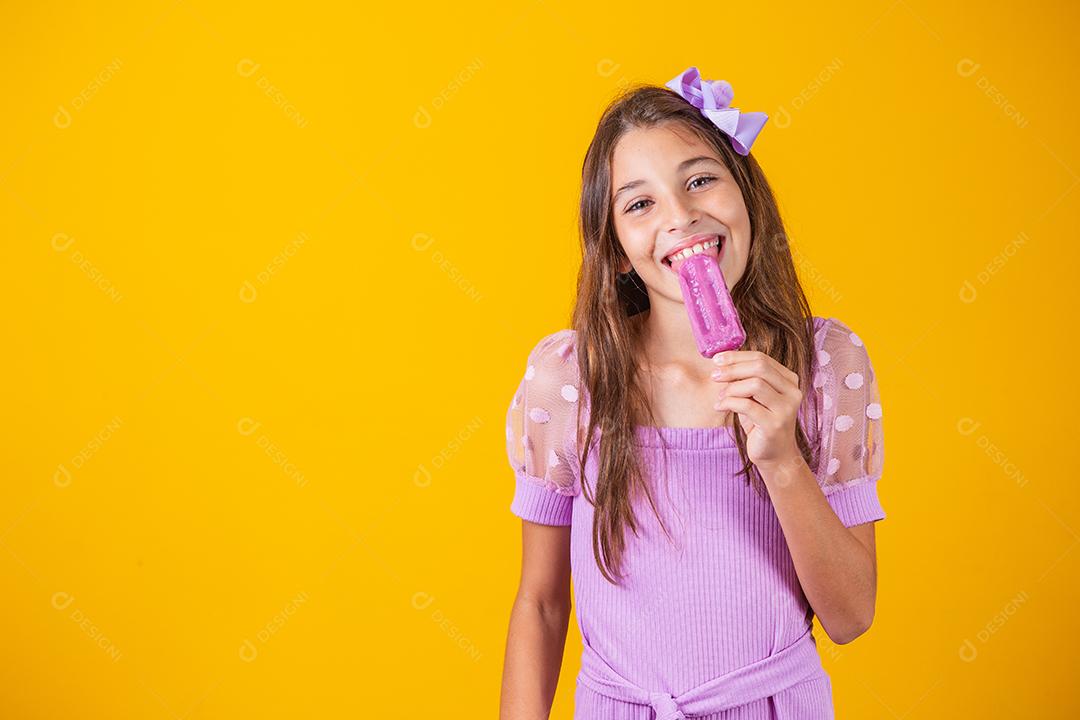 menina comendo um picolé congelado. Adorável menina com delicioso sorvete contra fundo de cor