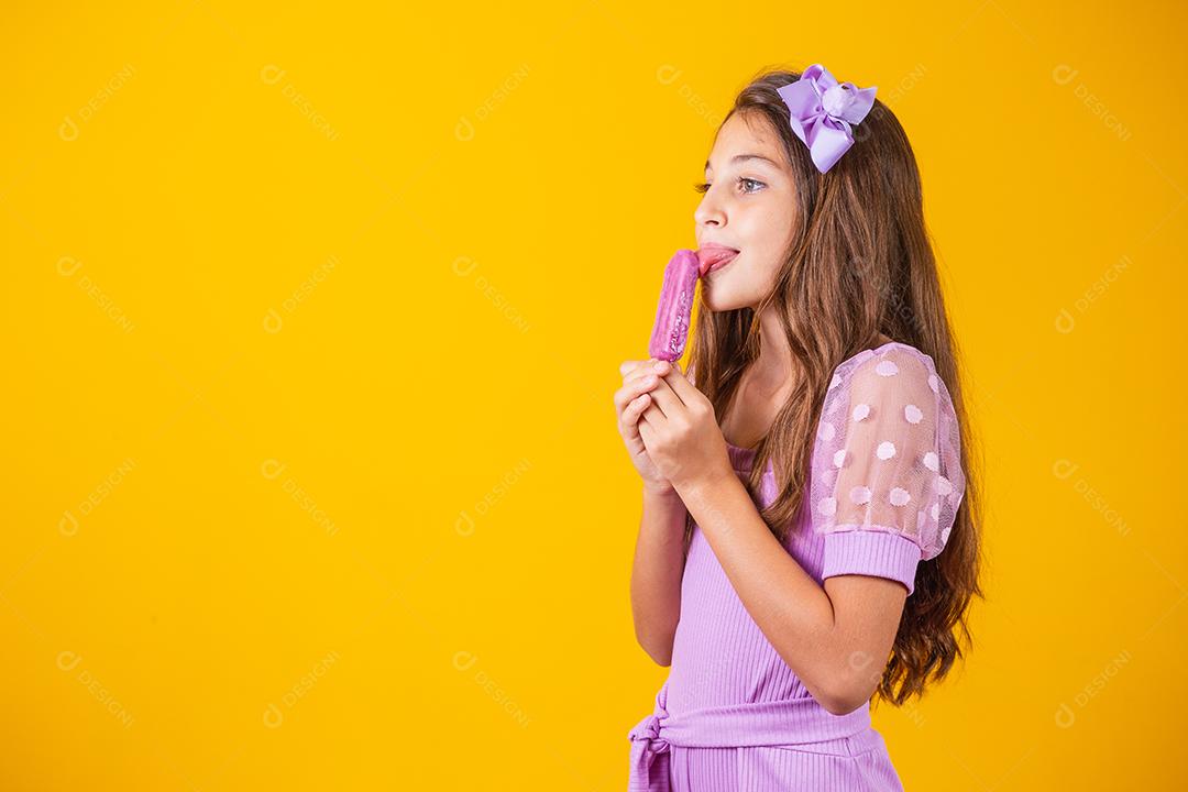 menina comendo um picolé congelado. Adorável menina com delicioso sorvete contra fundo de cor