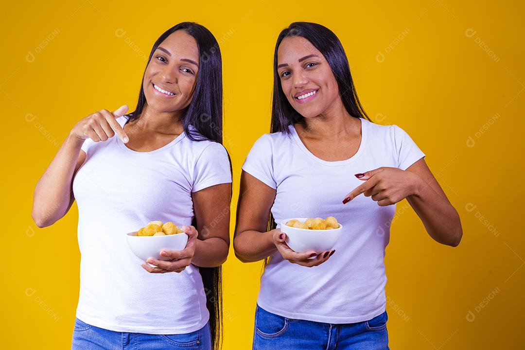 irmãs gêmeas comendo mini salgadinhos fritos