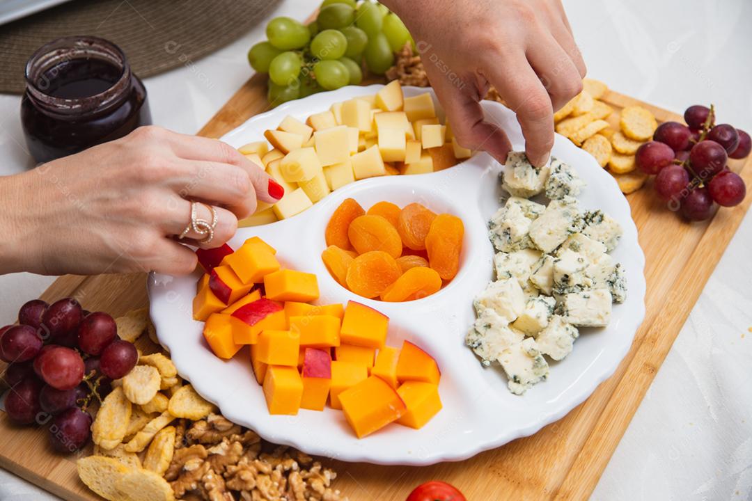 Prato de queijo com variedade de aperitivos na mesa.