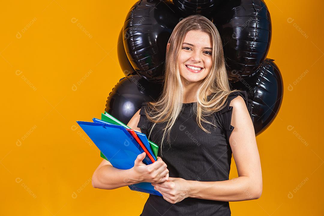 jovem mulher caucasiana sorrindo com notebooks nas mãos indo para a universidade na sexta-feira negra. conceito de equilíbrio na educação