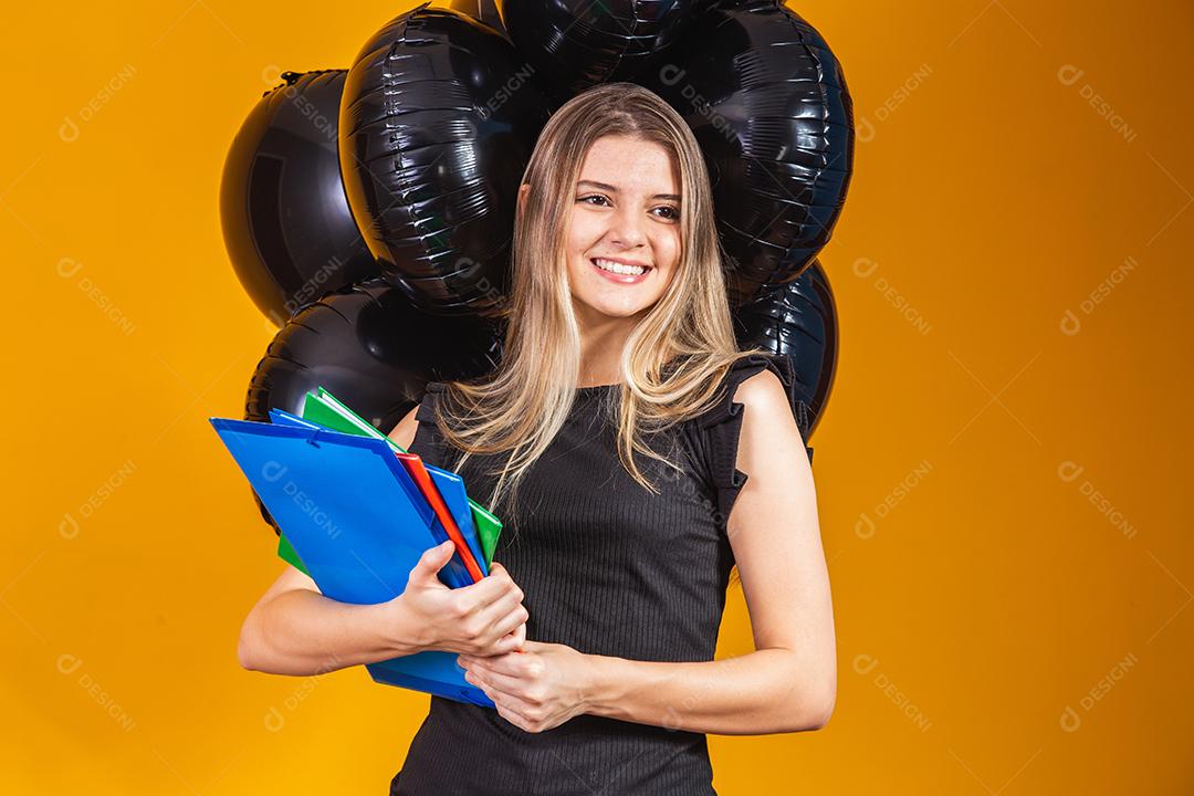 jovem mulher caucasiana sorrindo com notebooks nas mãos indo para a universidade na sexta-feira negra. conceito de equilíbrio na educação