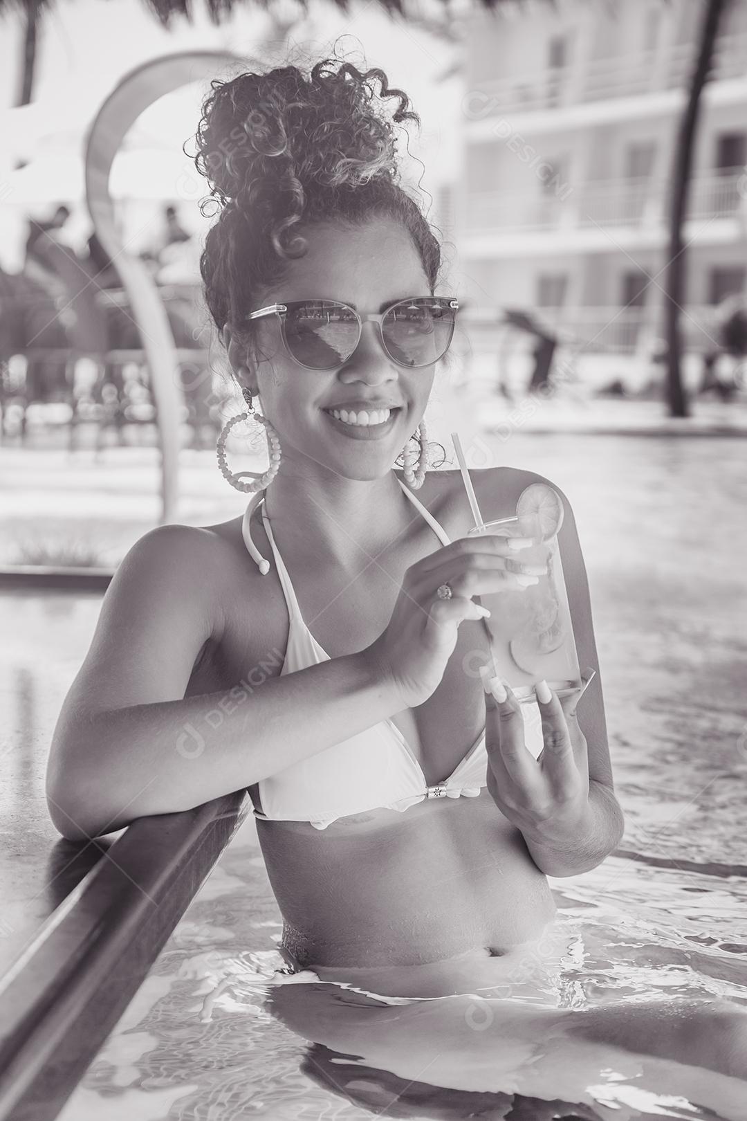 Jovem de férias na piscina do hotel tomando uma deliciosa bebida alcoólica.