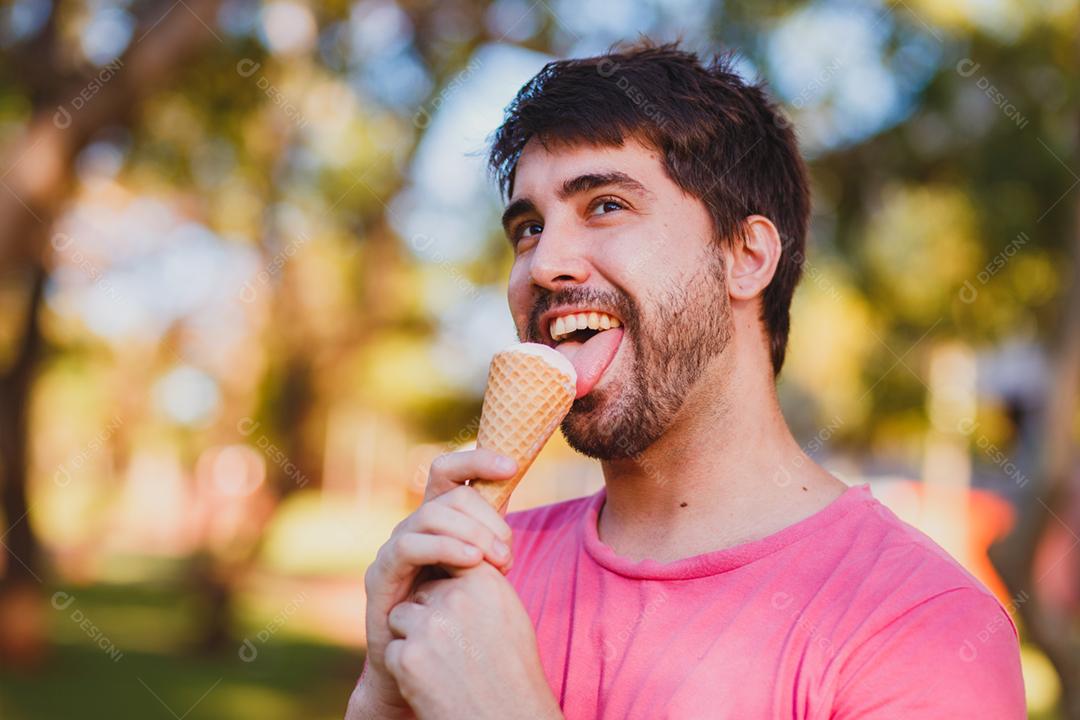 jovem bonito comendo sorvete no parque