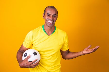 Foto Homem em calções amarelos segurando bola de futebol amarela e