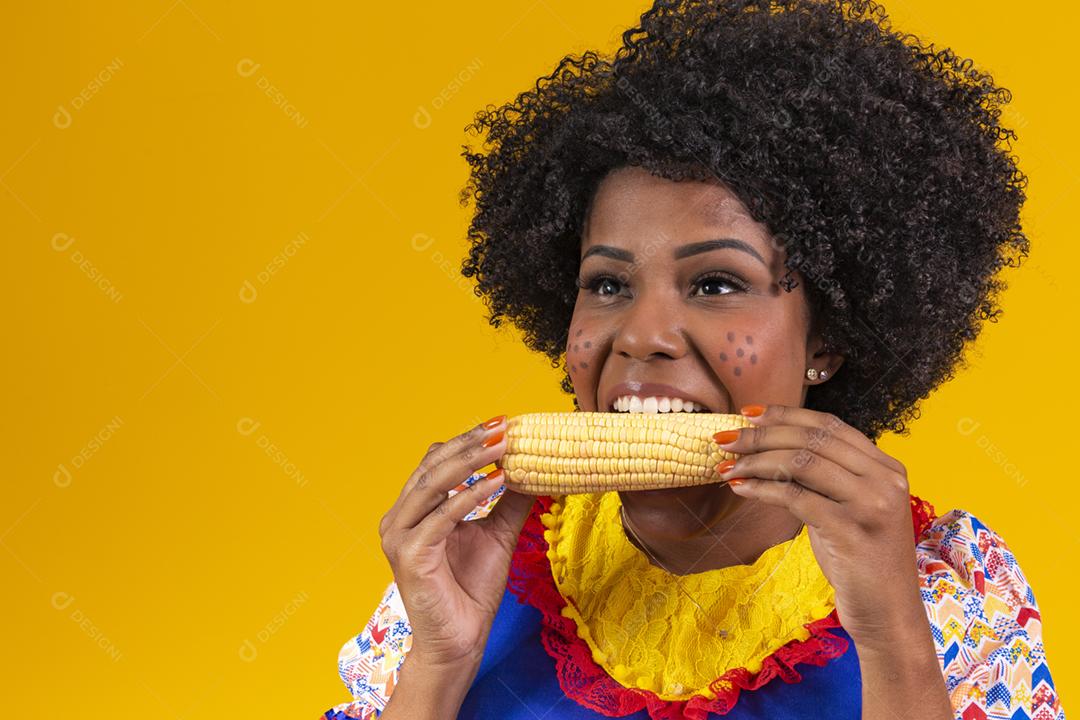 mulher bonita com roupas típicas festa junina comendo um milho cozido [download] - Designi