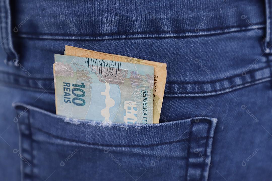 Dinheiro brasileiro real sobre um bolso de uma calça de uma pessoas brasileira
