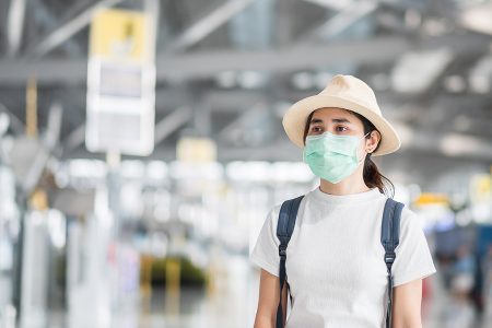 Mulher adulta jovem usando máscara cirúrgica no terminal do aeroporto ...