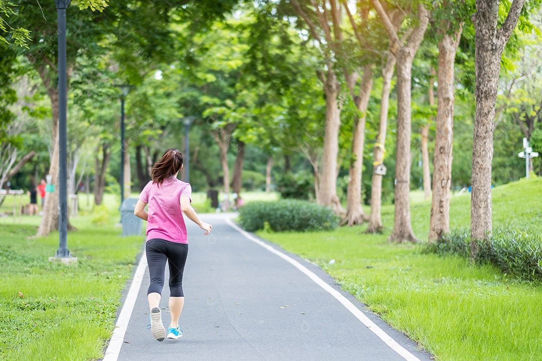 Mulher adulta jovem em roupas esportivas correndo no parque ao ar