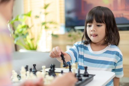 jovem concentrado desenvolvendo estratégia de xadrez, jogando jogo de  tabuleiro com os pais em casa. atividade ou hobby para o conceito de  família 9714365 Foto de stock no Vecteezy